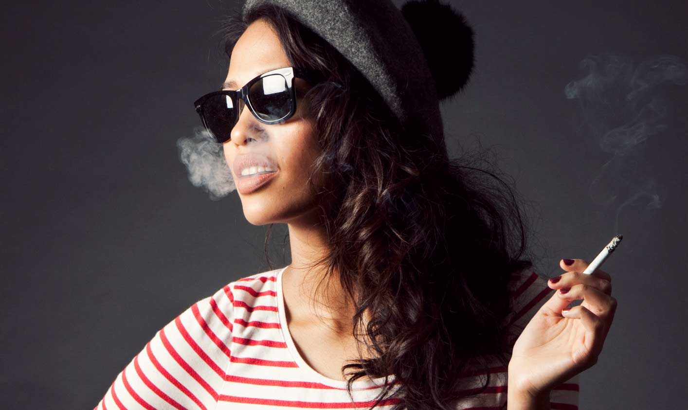 Women is sunglasses smoking a cigarette